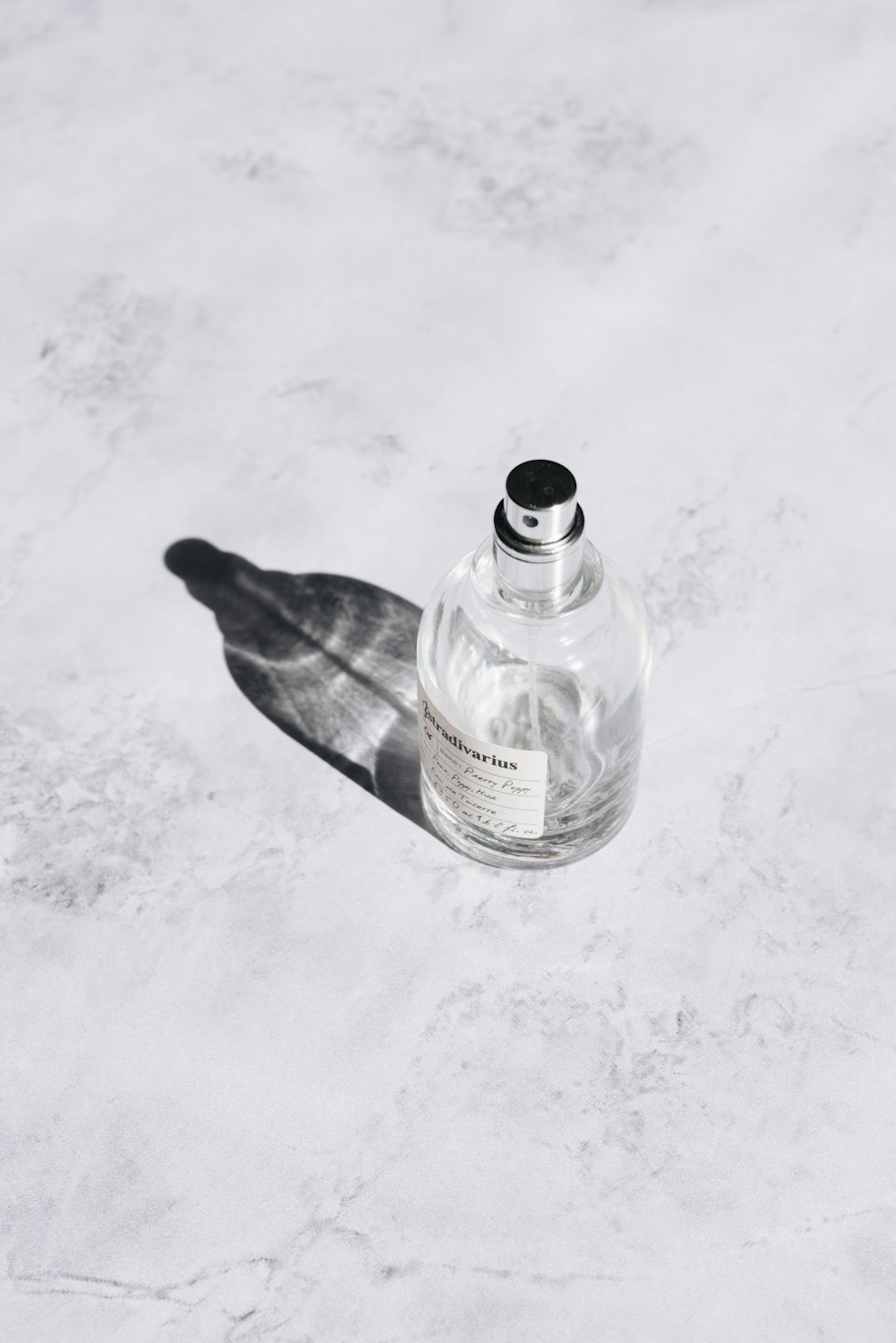 A perfume bottle with a silver and black cap on marble.